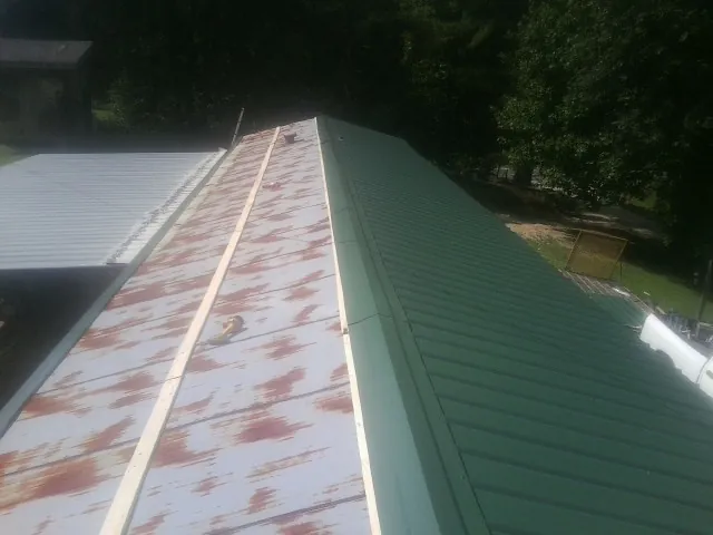 Old rusted panels beside newly installed green metal roofing — Wind Damage Roof Repair by Roofing Brothers in Atwater